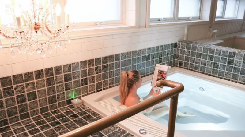 Kvinna l�ser tidningen i spapoolen p� Mora Hotell